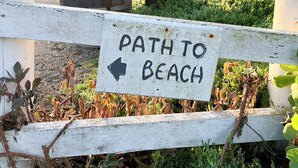 Un panneau en bois avec une flèche pointant vers la gauche, portant l'inscription « CHEMIN MENANT À LA PLAGE ».