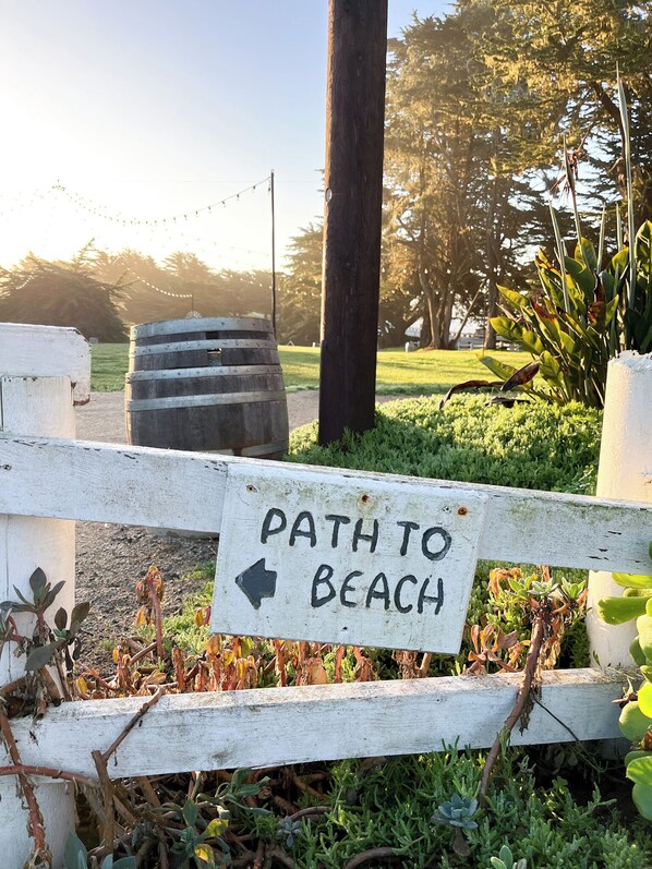 A wooden sign with an arrow pointing left, labeled "PATH TO BEACH". - Oceanpoint Ranch (Cambria)