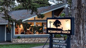 Une enseigne pour Oceanpoint Ranch, représentant une silhouette de coucher de soleil, un mur de pierre et un bâtiment doté d’un toit en pente.