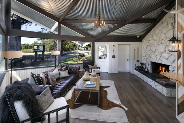 A spacious living room with a leather sofa, a coffee table, and a stone fireplace.