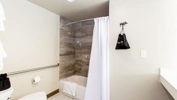 A bathroom with a shower, toilet, and a towel rack with a bag.