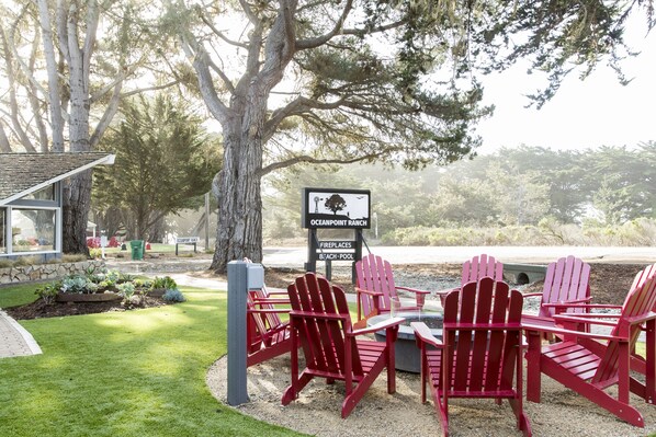 A patio with red Adirondack chairs, a sign for Oceanpoint Ranch, and a stone building in the background.