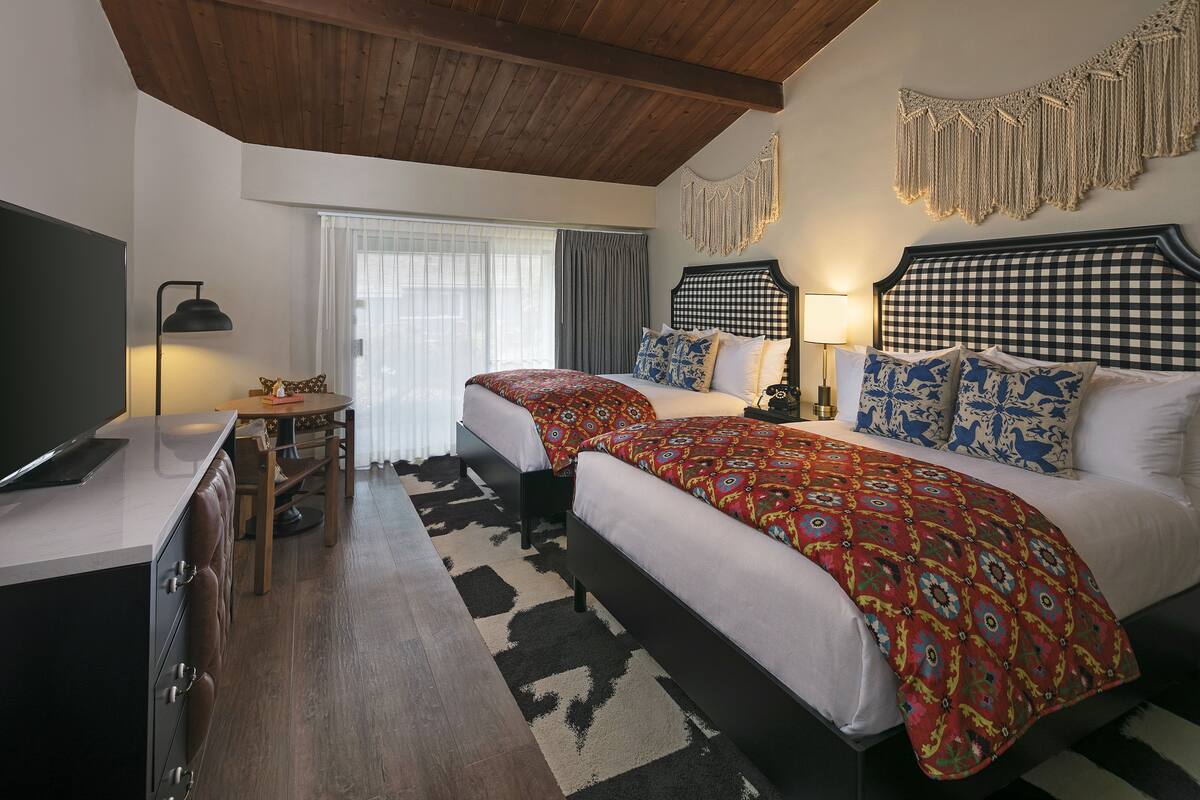 A bedroom with two beds, a desk, and a chair.