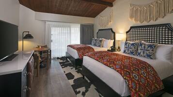 A bedroom with two beds, a desk, and a chair.