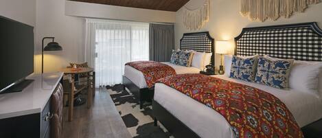 A bedroom with two beds, a desk, and a chair.