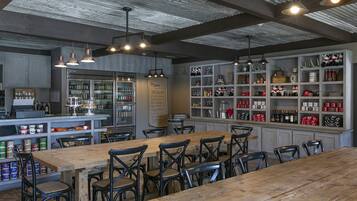 A rustic bar area with wooden tables and metal chairs, shelves with bottles and decorative items, and a menu board.