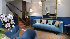 A room with a blue sofa, two blue armchairs, a large mirror, and a staircase. - Hotel Mogador Opera - Paris (Paris)