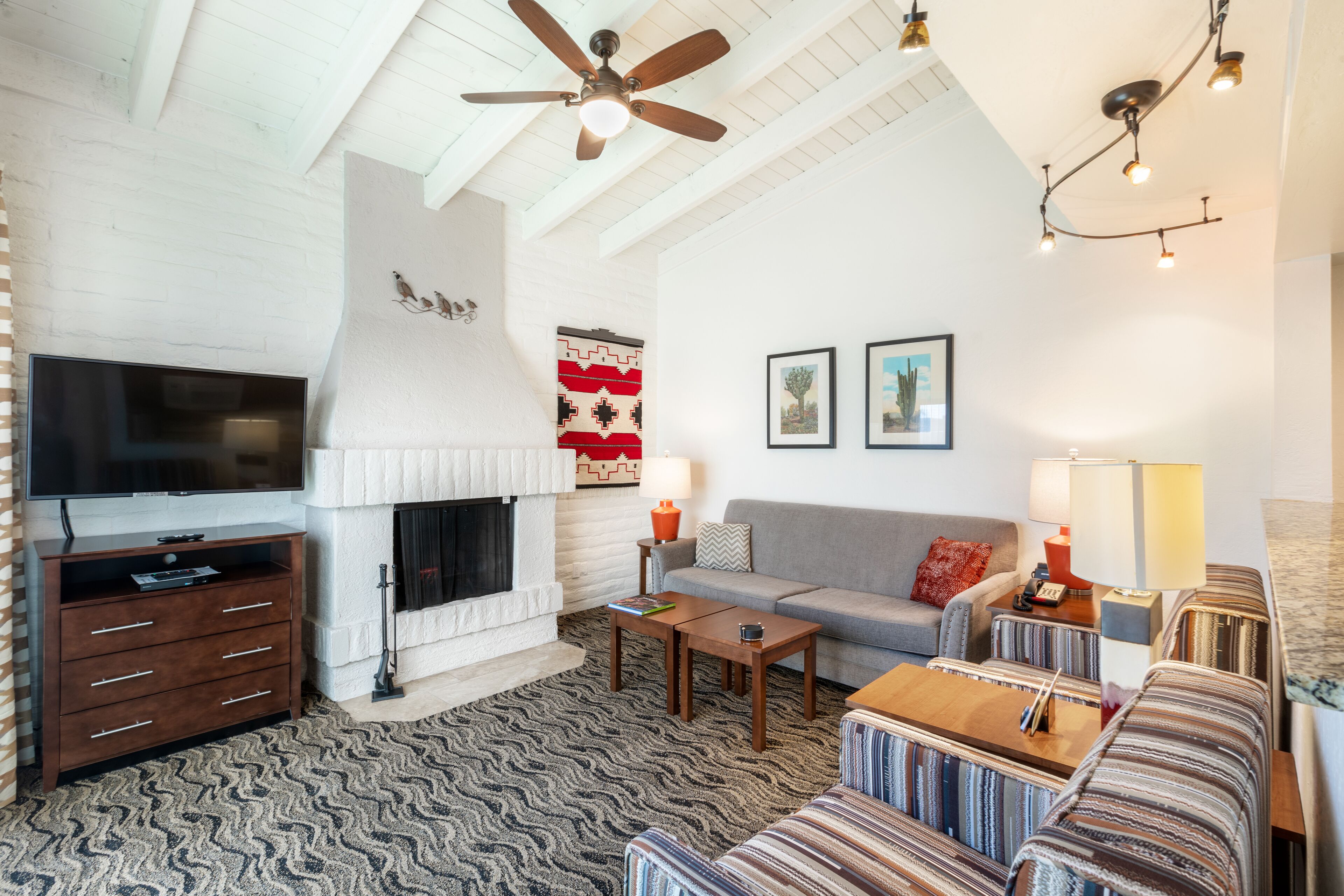 A living room with a fireplace, television, sofa, and patterned rug.