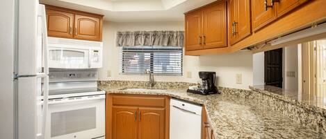 A kitchen with wooden cabinets, a white refrigerator, a microwave, an oven, and a dishwasher.