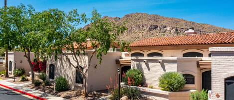 A residential building with a tiled roof, arched windows, and a landscaped garden with desert plants.