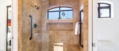 A modern bathroom with a walk-in shower, a toilet, and a window with a view.