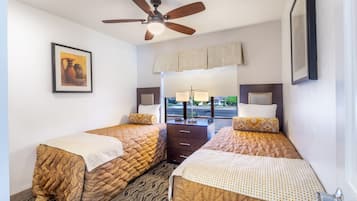 Habitación de hotel con dos camas, un ventilador de techo, un cuadro en la pared y una ventana con vista a la calle.