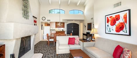 A spacious living room with a fireplace, two sofas, a coffee table, and a ceiling fan.