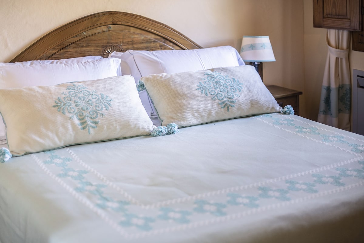 A neatly made bed with a floral-patterned bedspread and matching pillows.