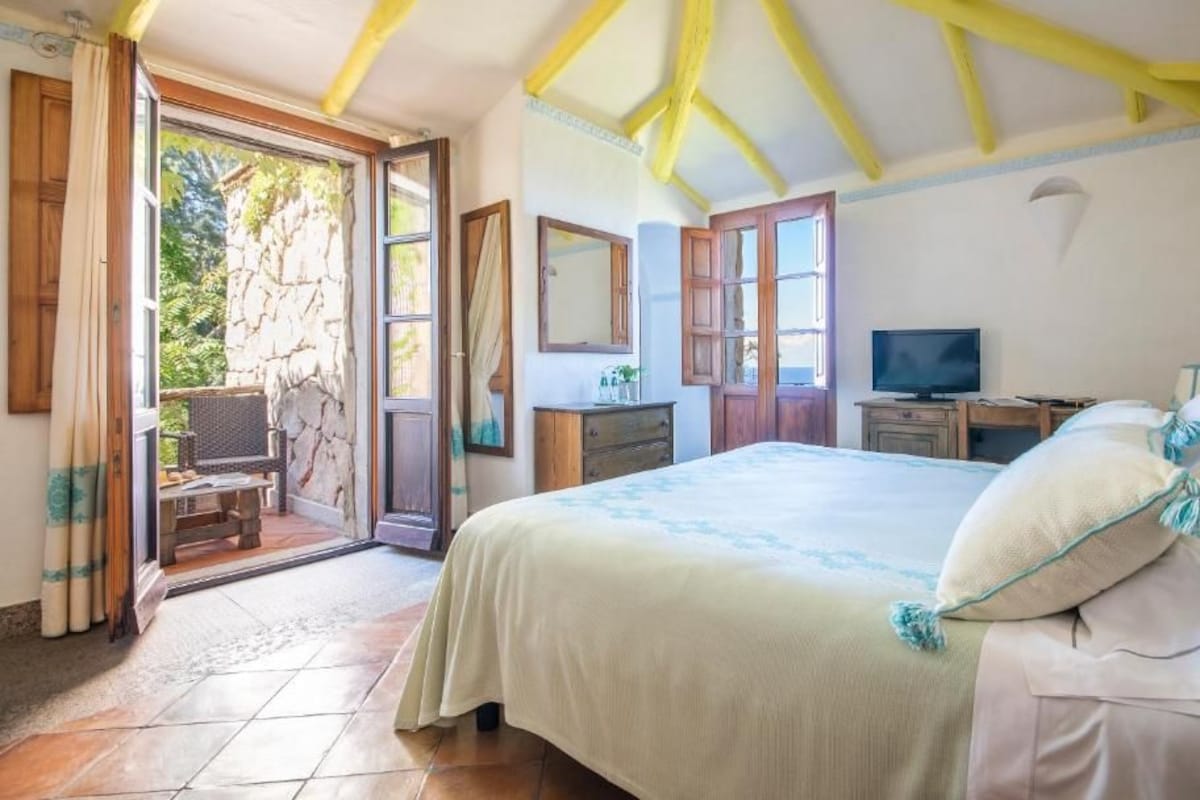 Ein Schlafzimmer mit Bett, Schreibtisch, Fernseher und einer Steinwand.