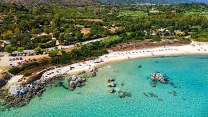 An aerial view of a coastal area with a beach, clear turquoise waters, and rocky outcrops. - Hotel Monte Turri by Falkensteiner (Tortoli)