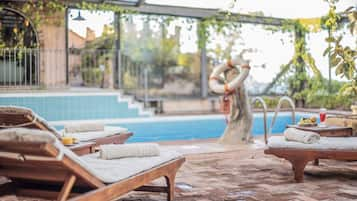 Una piscina al aire libre de temporada, sombrillas