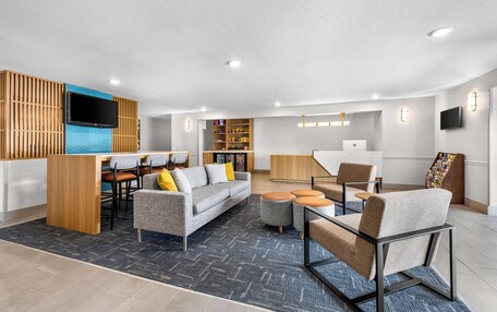 A modern living room with a sofa, chairs, a coffee table, and a TV mounted on the wall.