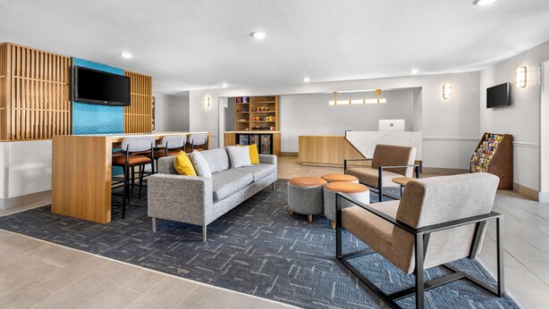 Un salon moderne avec un canapé, des fauteuils, une table basse et un téléviseur fixé au mur.