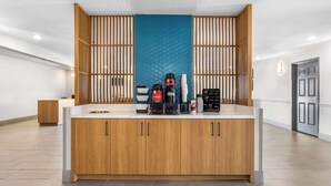 Une cuisine moderne avec des meubles en bois, un îlot central et divers appareils électroménagers, notamment une machine à café et une bouilloire.