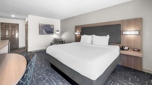 Une chambre d’hôtel avec un grand lit, des tables de chevet, un bureau et une chaise.