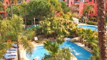 A pool area with lounge chairs, palm trees, and a small waterfall feature.