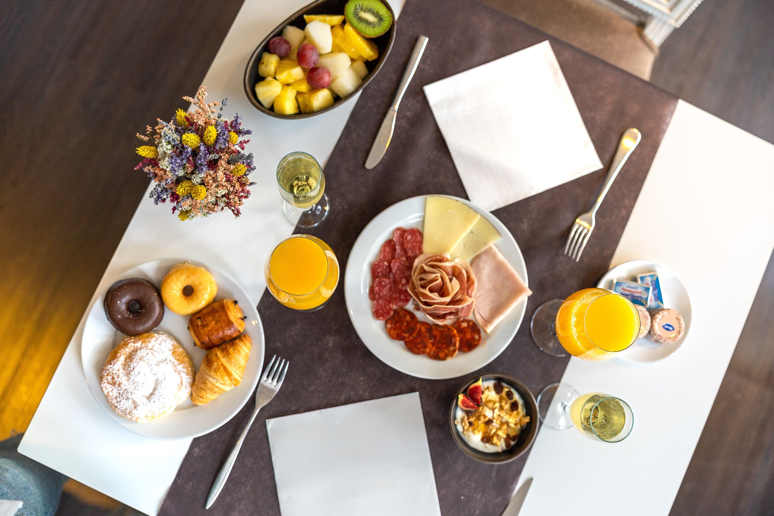 A breakfast table with various food items, including pastries, fruits, and beverages.