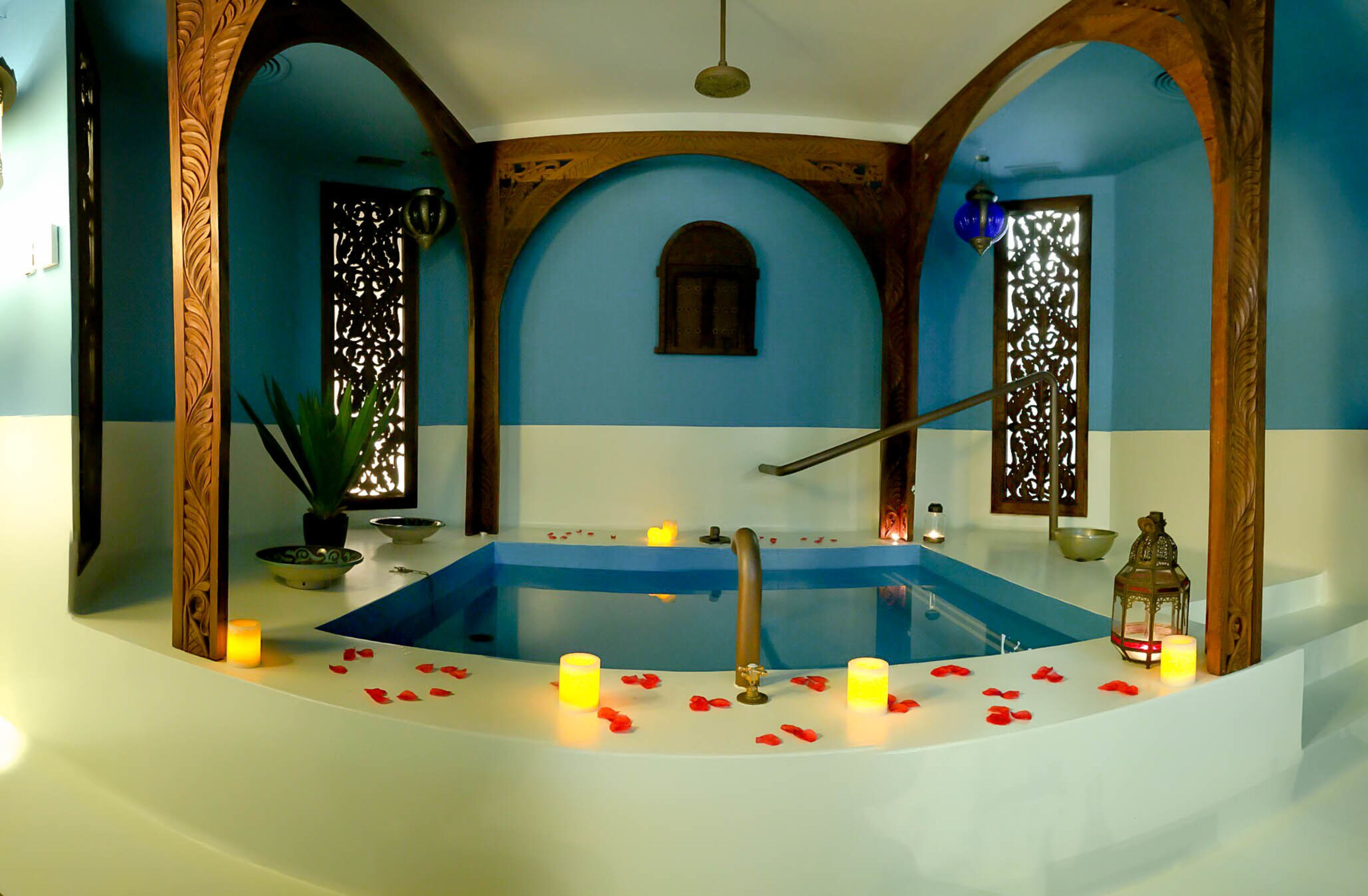A spa area with a bathtub, candles, and decorative elements.