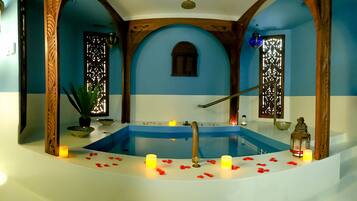A spa area with a bathtub, candles, and decorative elements.