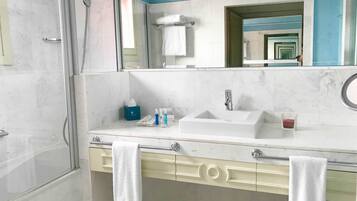 Un baño moderno con cabina de ducha de vidrio, un lavabo blanco y un espejo grande.