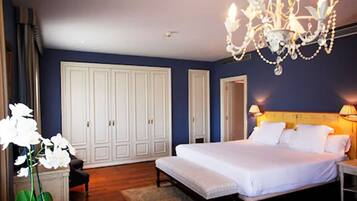 Een slaapkamer met een groot bed, een kroonluchter, een garderobe en een nachtkastje.
