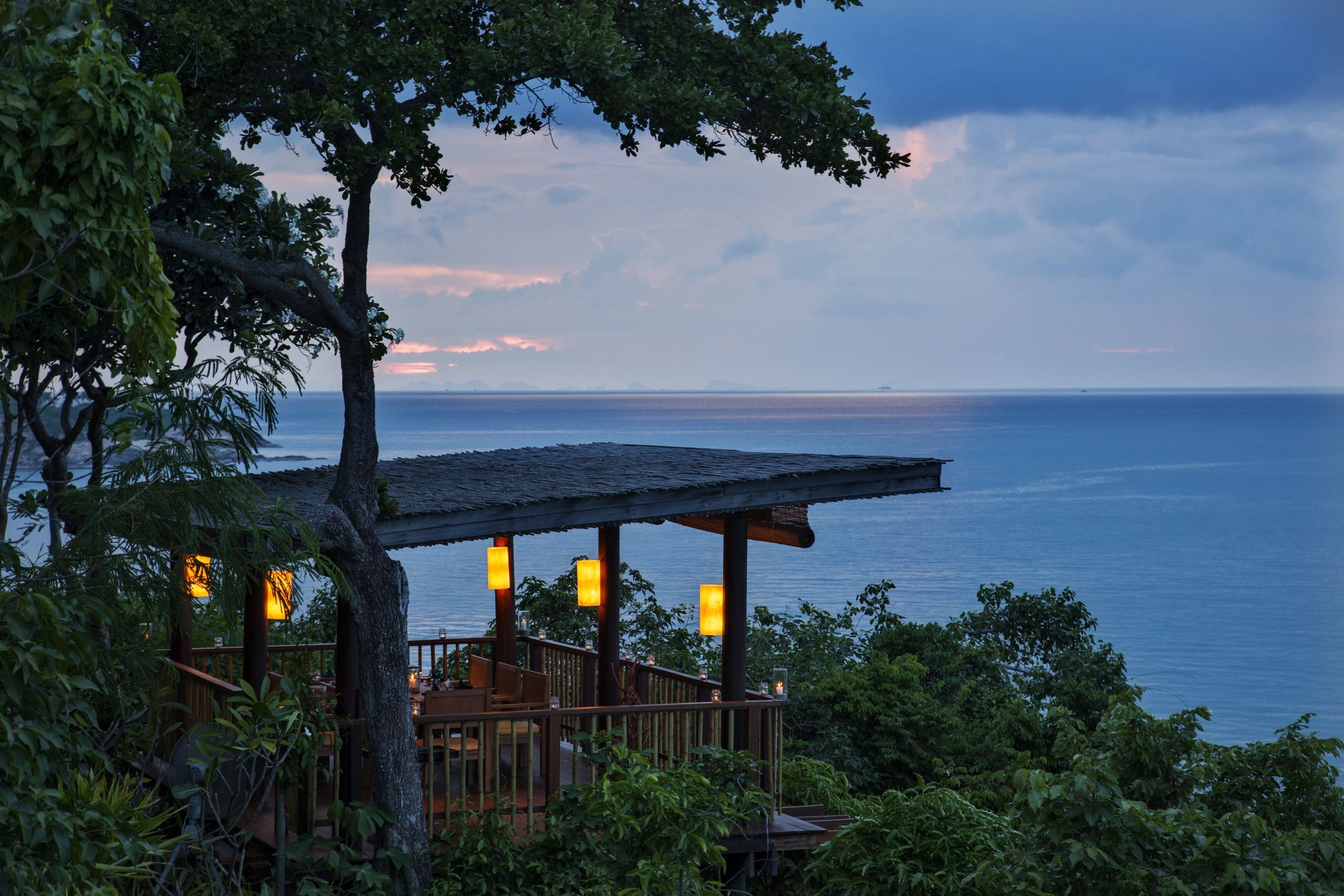 A wooden deck with a railing overlooking a body of water, surrounded by trees.