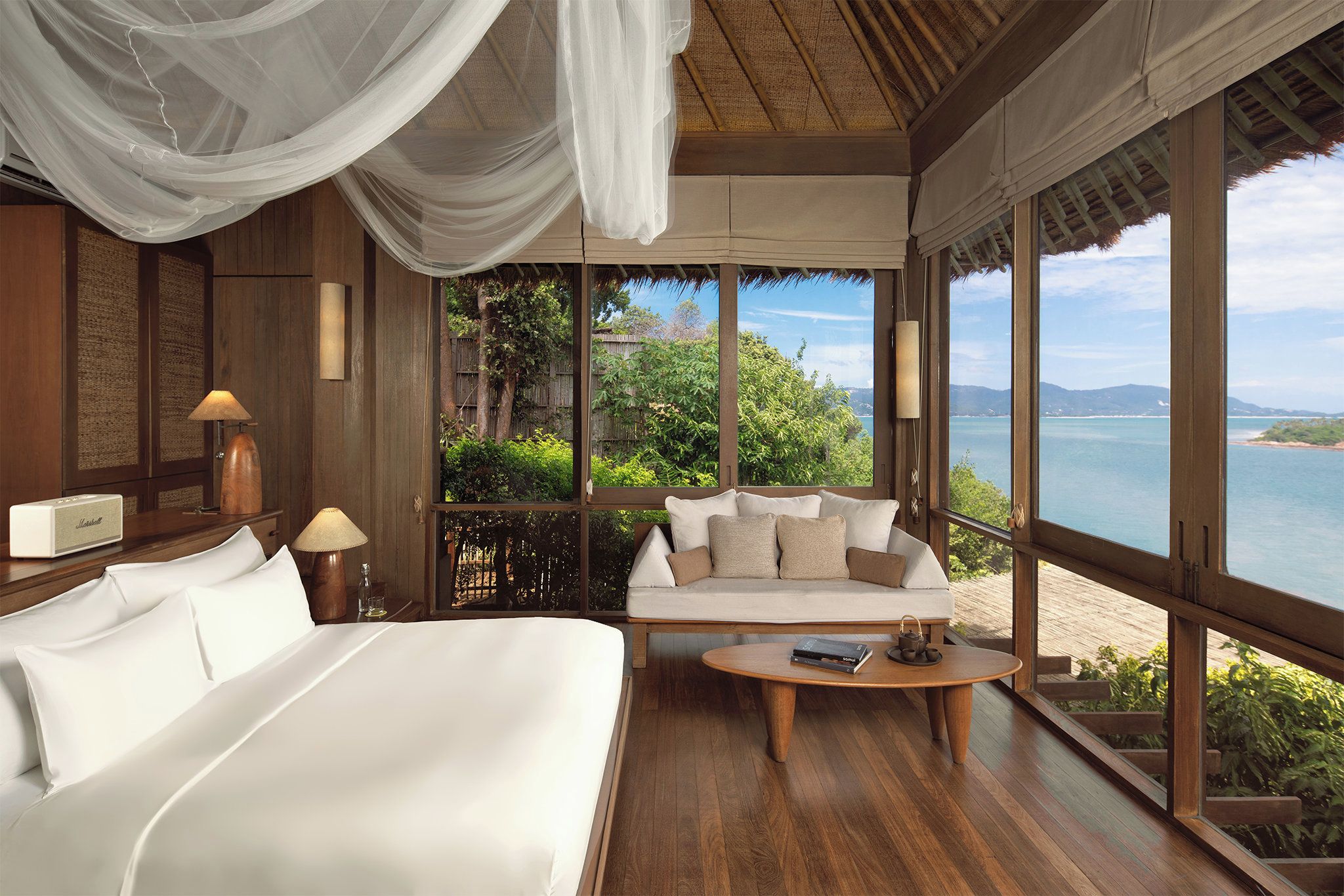 Un dormitorio con una cama grande, un sofá, una mesita de centro y vistas al mar.