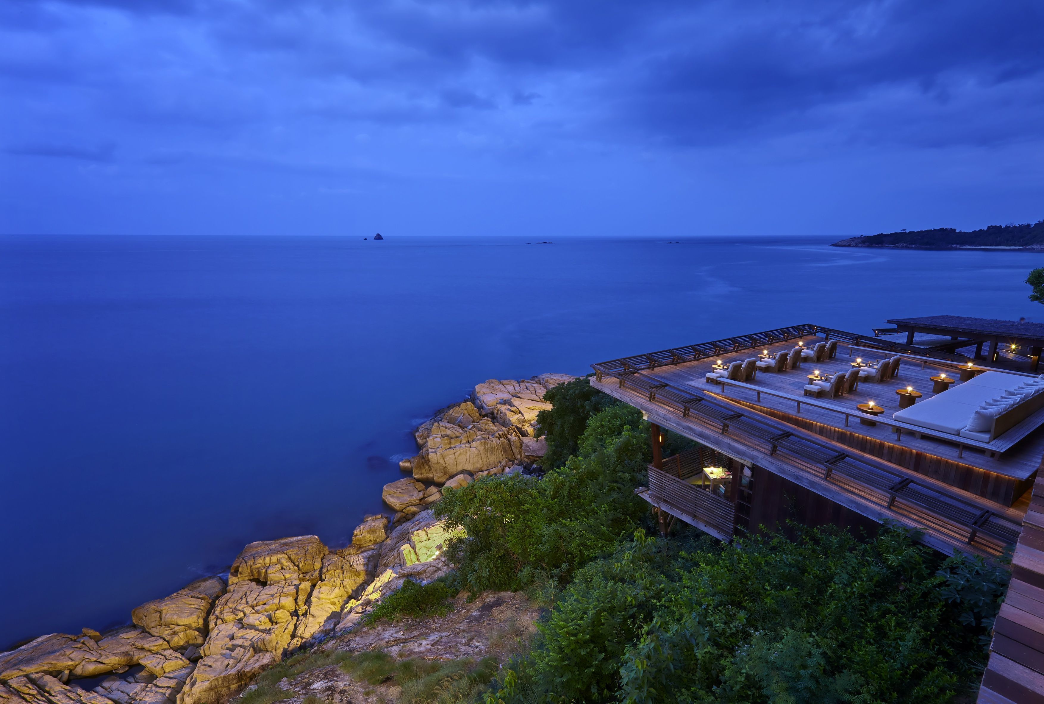 Un hôtel situé sur la côte, doté d’une terrasse extérieure avec vue sur la mer, comprenant une plateforme en bois et un espace détente.