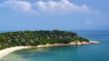 Una isla tropical con playa y bungalós sobre el agua.