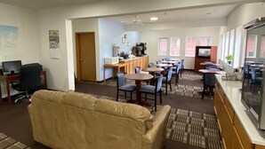 A hotel lobby with a seating area, a kitchenette, and a TV. - Super 8 by Wyndham Ida Grove (Ida Grove)