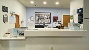 A reception area with a counter, informational posters, and a Super 8 logo on the floor. - Super 8 by Wyndham Ida Grove (Ida Grove)