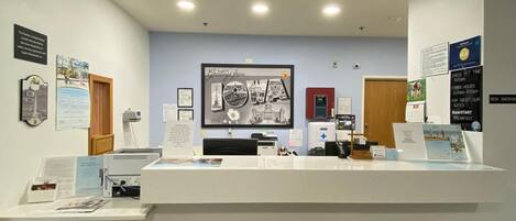 A reception area with a counter, informational posters, and a Super 8 logo on the floor.