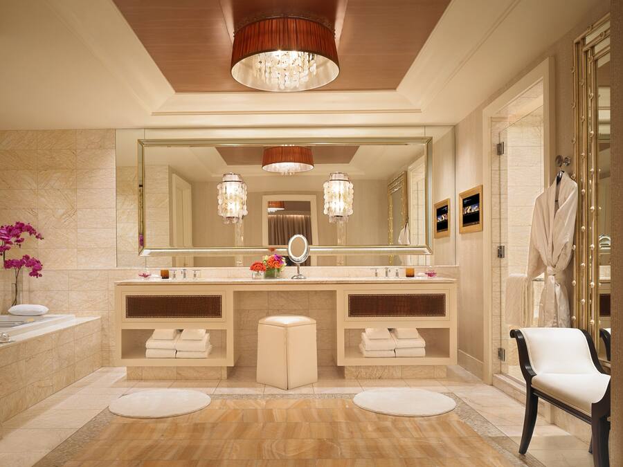 Un baño lujoso con tocador doble, espejo grande, candelabro y un perchero para bata.