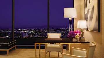 Une chambre d’hôtel moderne dotée d’une grande fenêtre donnant sur la ville, avec une vue particulièrement agréable la nuit.