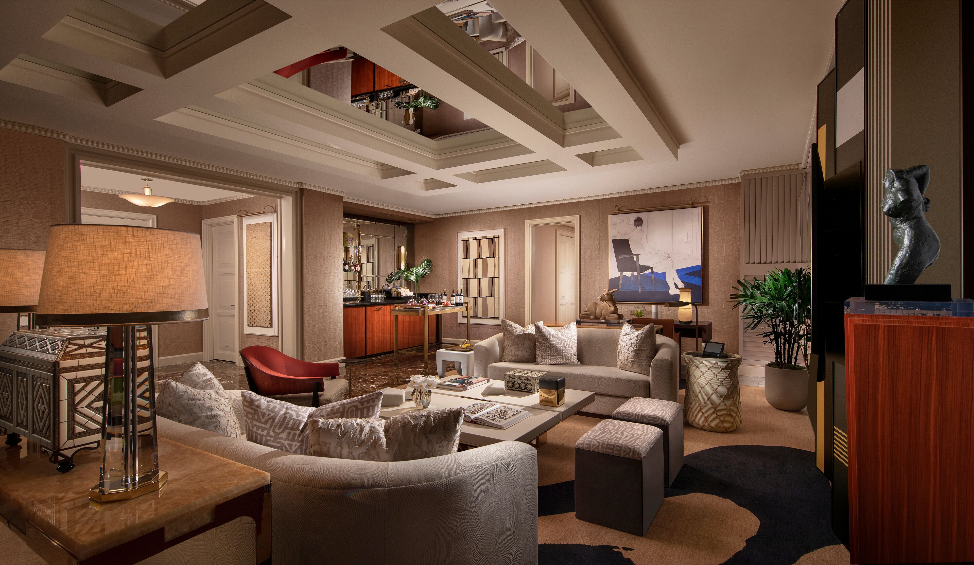 A spacious living room with a high ceiling, a bar area, and a staircase leading to an upper level.