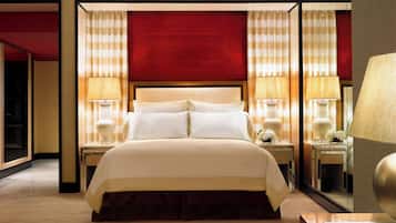 A hotel room with a large bed, two bedside tables with lamps, a mirror, and a wooden floor.