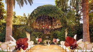 A formal outdoor setting with a floral arrangement, a table, and chairs arranged for an event. - Wynn Las Vegas (Las Vegas)