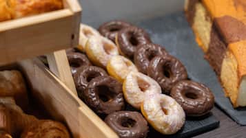 A variety of donuts and pastries in wooden and black trays.