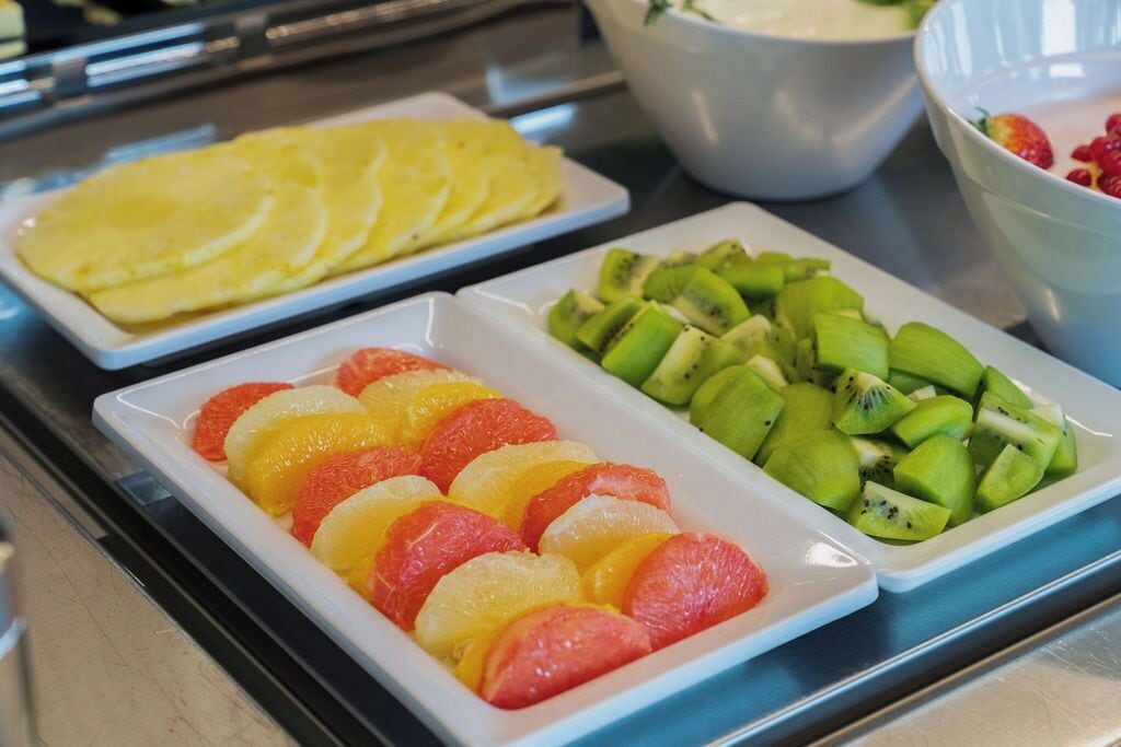 A buffet table with plates of sliced fruits including oranges, grapefruits, and kiwi.
