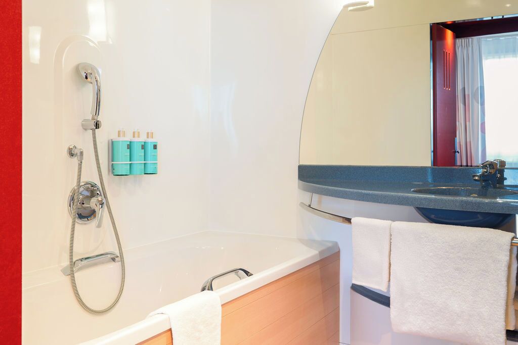 A modern bathroom with a bathtub, a shower, and a sink. There are two towels hanging on the wall.
