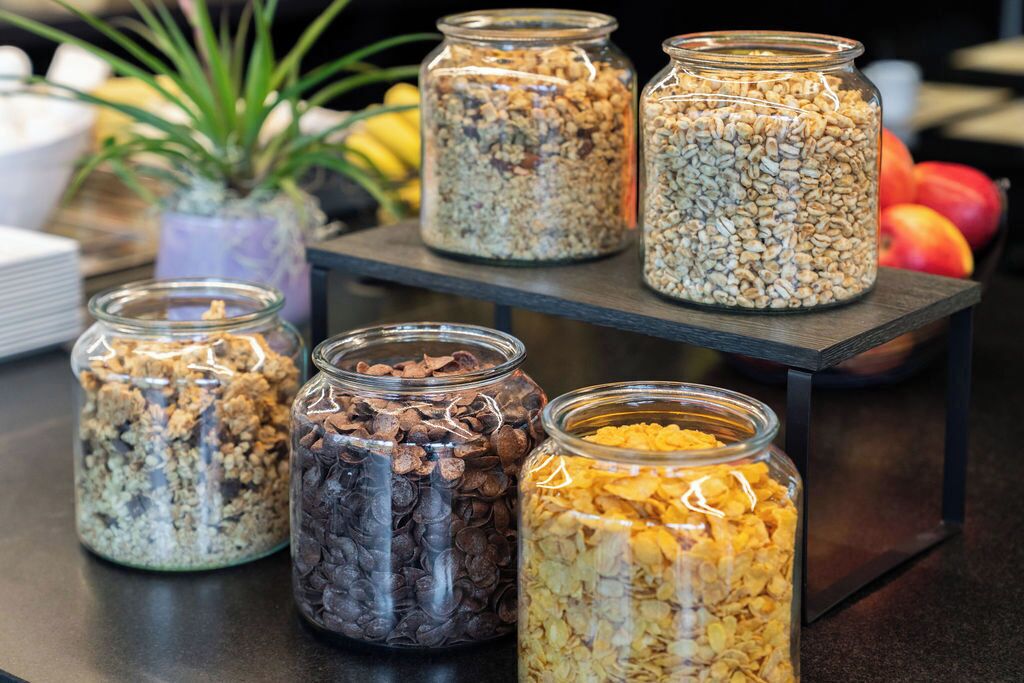 Una variedad de botes con granola y cereales en un estante.