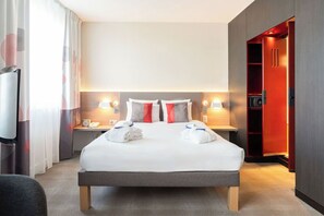 A hotel room with a large bed, bedside tables with lamps, a TV, and a wardrobe. - Novotel Suites Geneve Aeroport (Vernier)