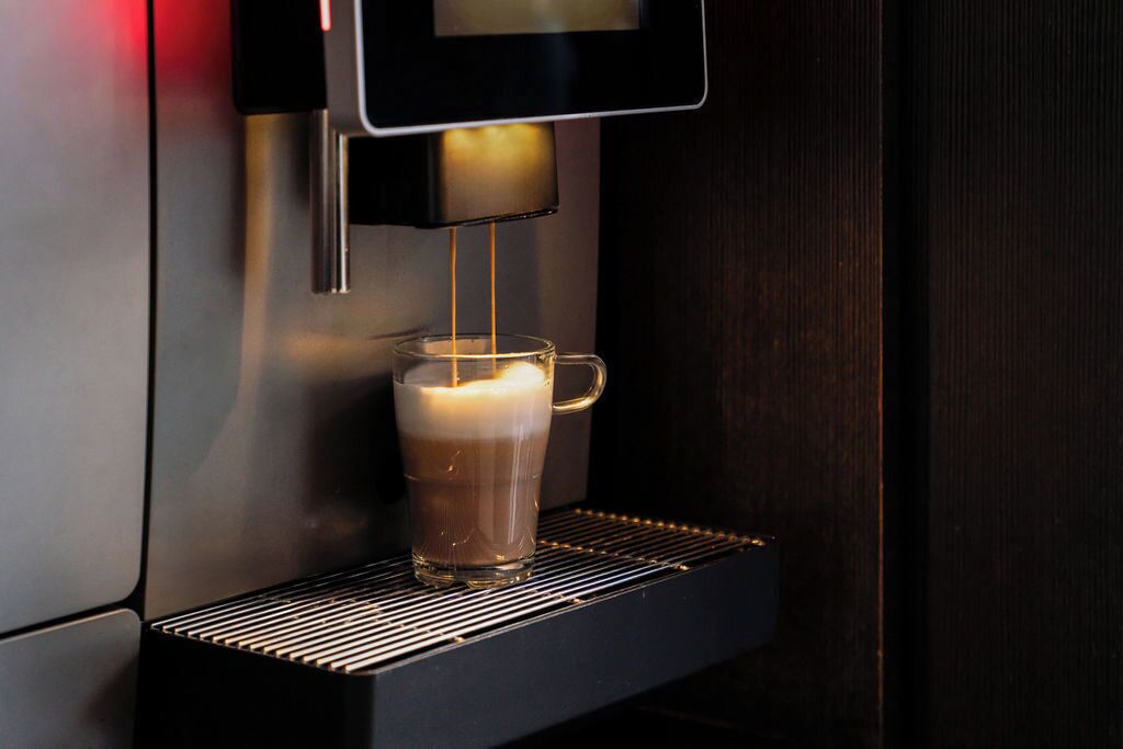 Une machine à café verse du café dans une tasse en verre transparent.