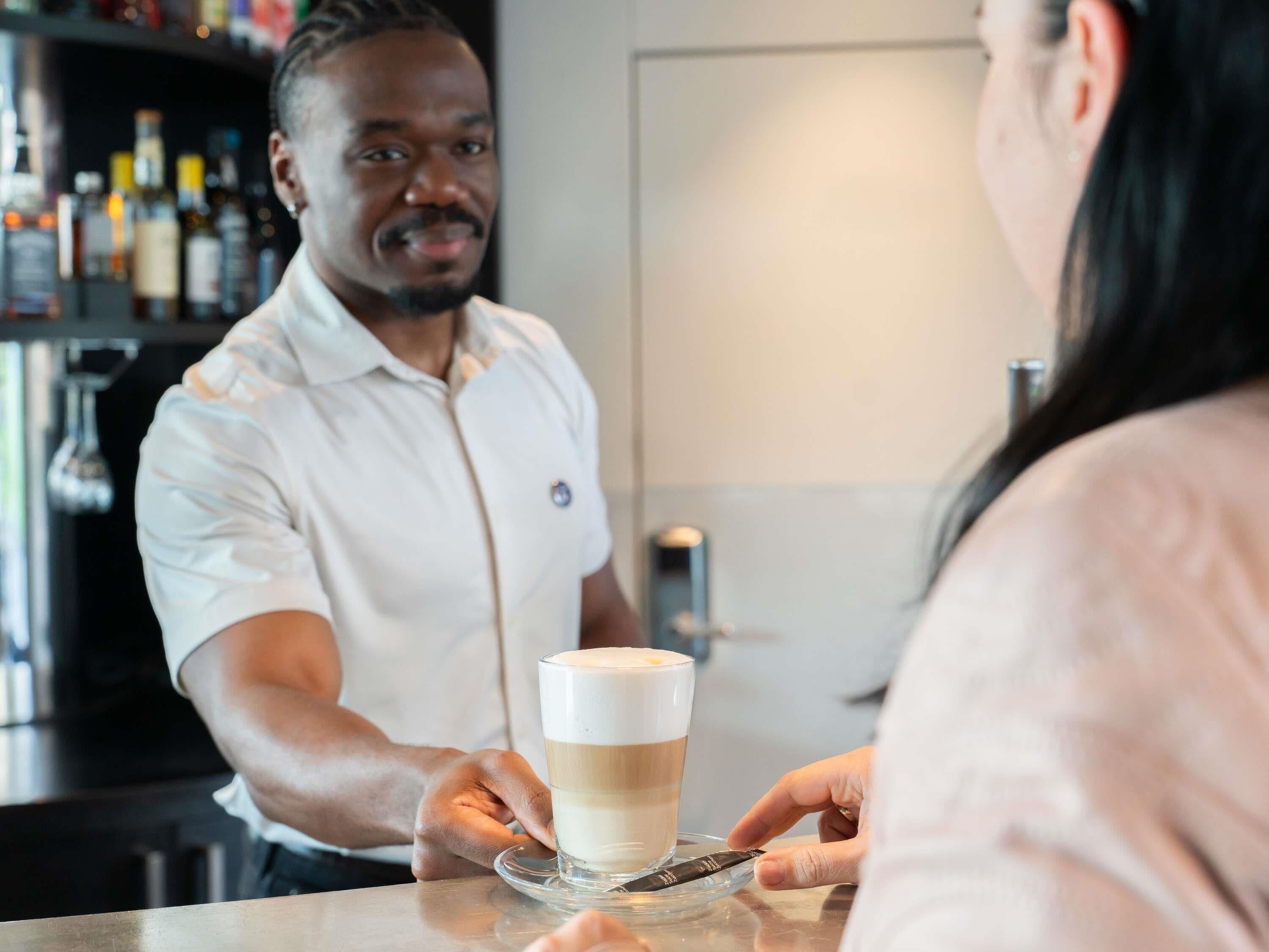 A bar setting with a person serving a layered beverage.